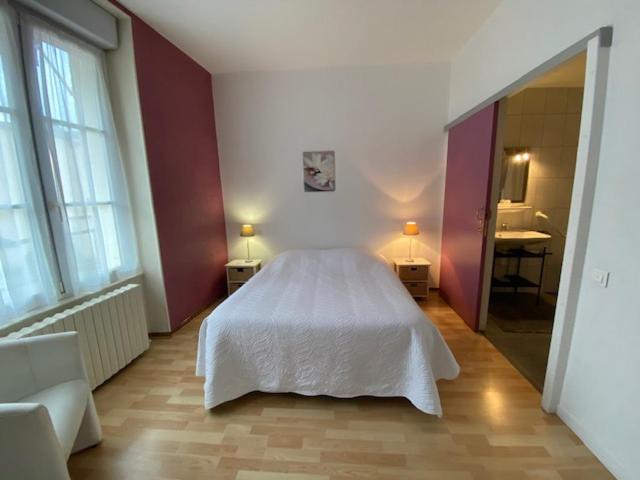 a bedroom with a white bed and a bathroom at Pension Gérard in Bourbonne-les-Bains