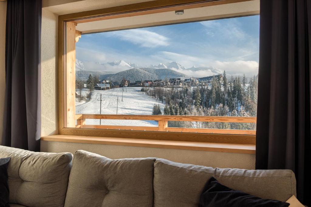 uma janela com vista para uma montanha coberta de neve em Tatrzańska Polana 5F em Zakopane
