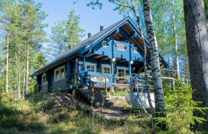 a blue house in the middle of a forest at Ilmajärvi Cottage in Ruokolahti
