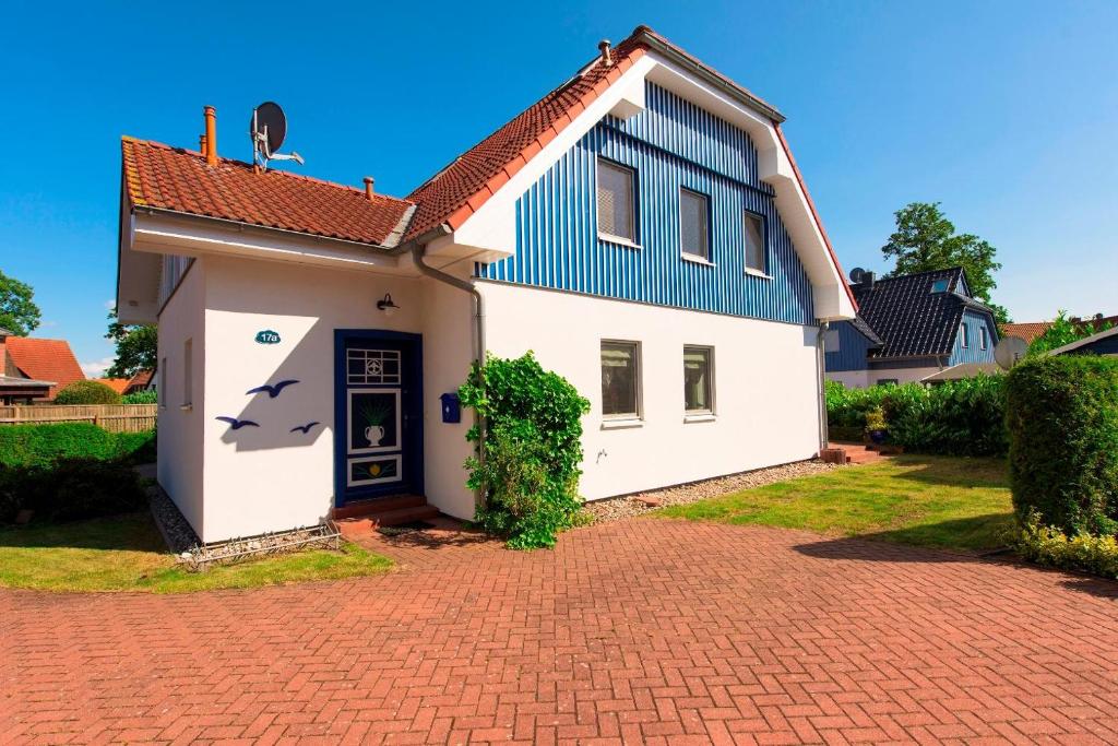 ein weißes Haus mit einem blauen Dach und einer steinernen Einfahrt in der Unterkunft Wiesenstrasse in Zingst