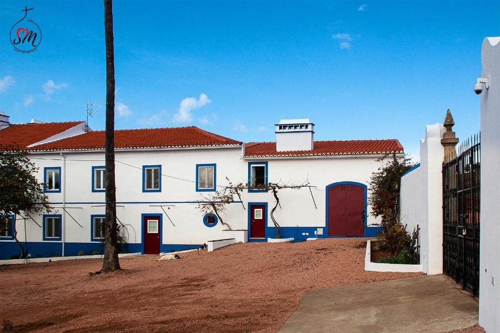 ein weißes Gebäude mit roten Türen und einem roten Dach in der Unterkunft Quinta da Fortaleza in Elvas