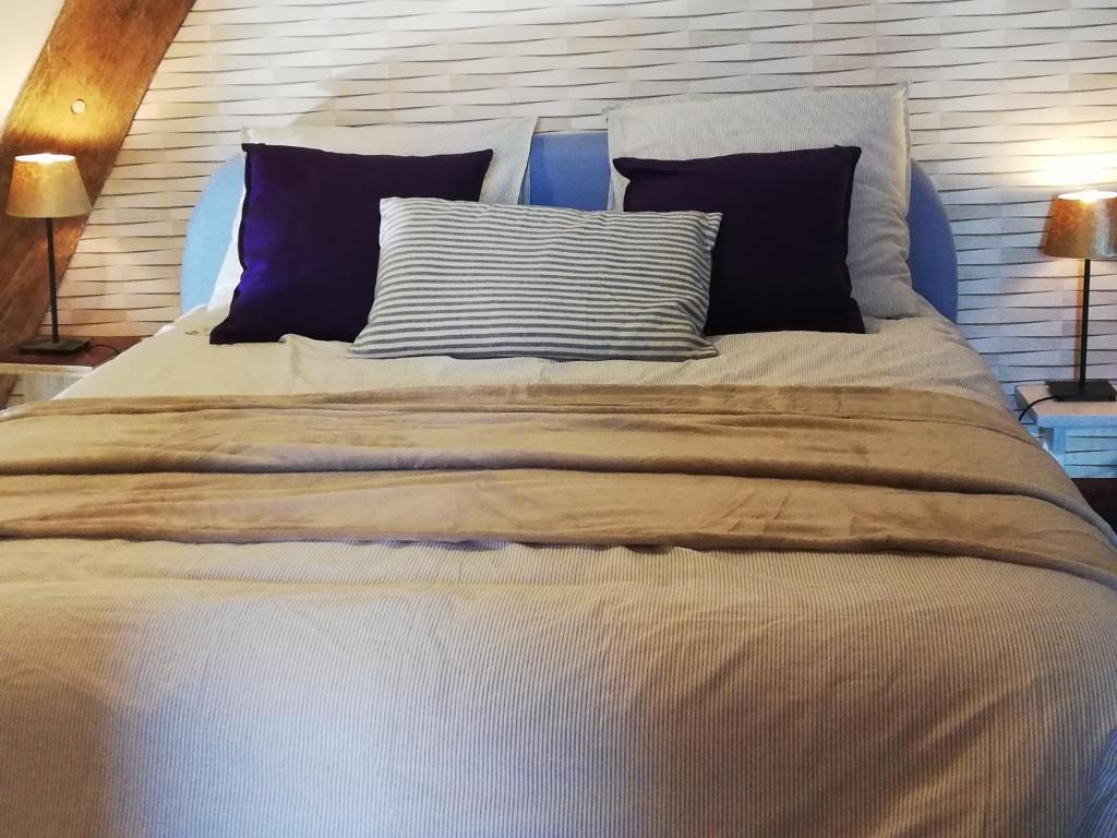 uma cama grande com duas almofadas em cima em Le Monticule em Tardes