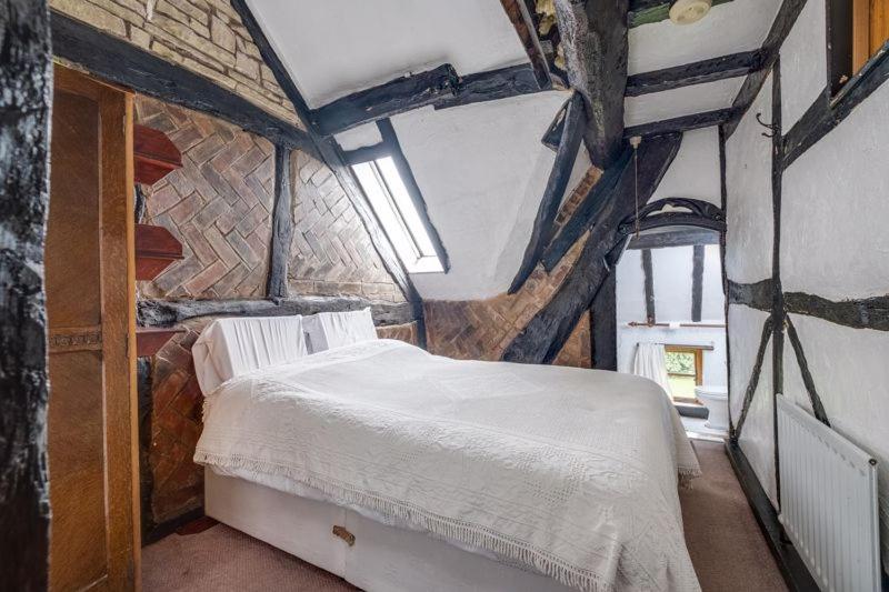 1 dormitorio con 1 cama blanca en una pared de ladrillo en The Old Rectory, en Coleshill