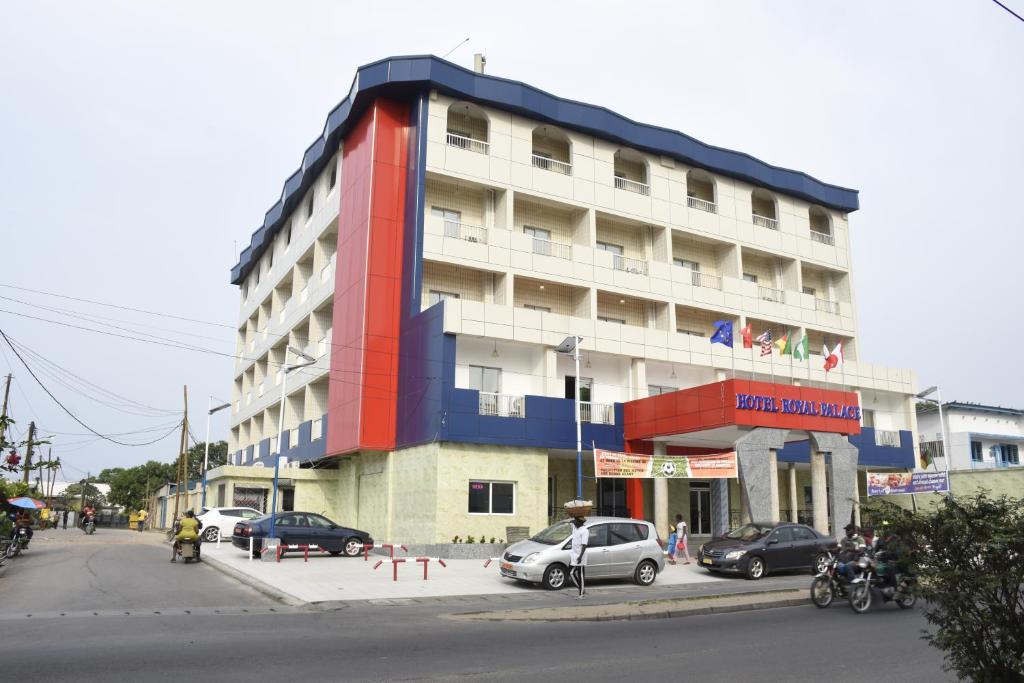 un grand bâtiment avec des voitures garées devant lui dans l'établissement Hotel Royal Palace, à Douala