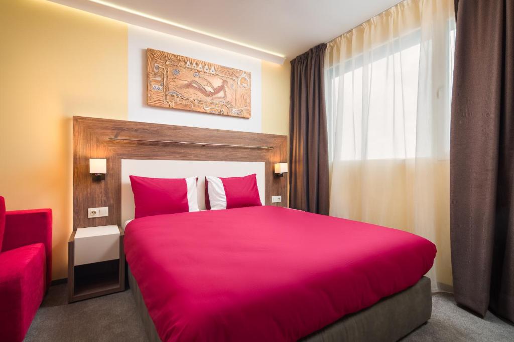 1 dormitorio con 1 cama rosa grande y ventana en АРТ СТУДИО СОФИЯ en Sofía