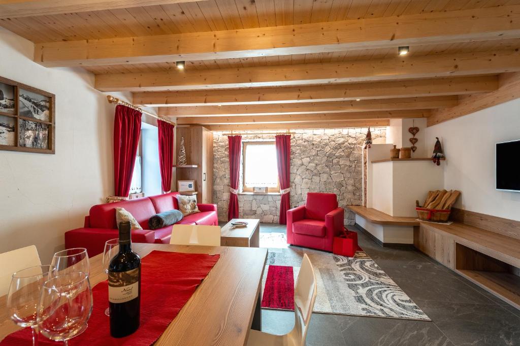 ein Wohnzimmer mit roten Möbeln und einer Flasche Wein in der Unterkunft Ciasa Sas da le Doudesc in Vigo di Fassa