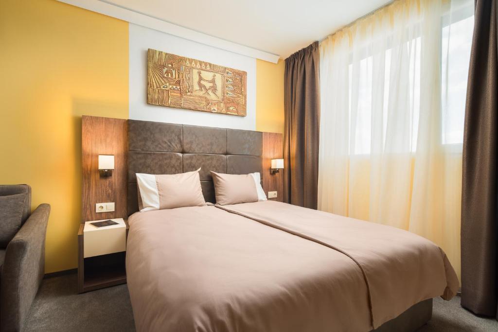 a bedroom with a large bed and a chair at АРТ СТУДИО СОФИЯ in Sofia
