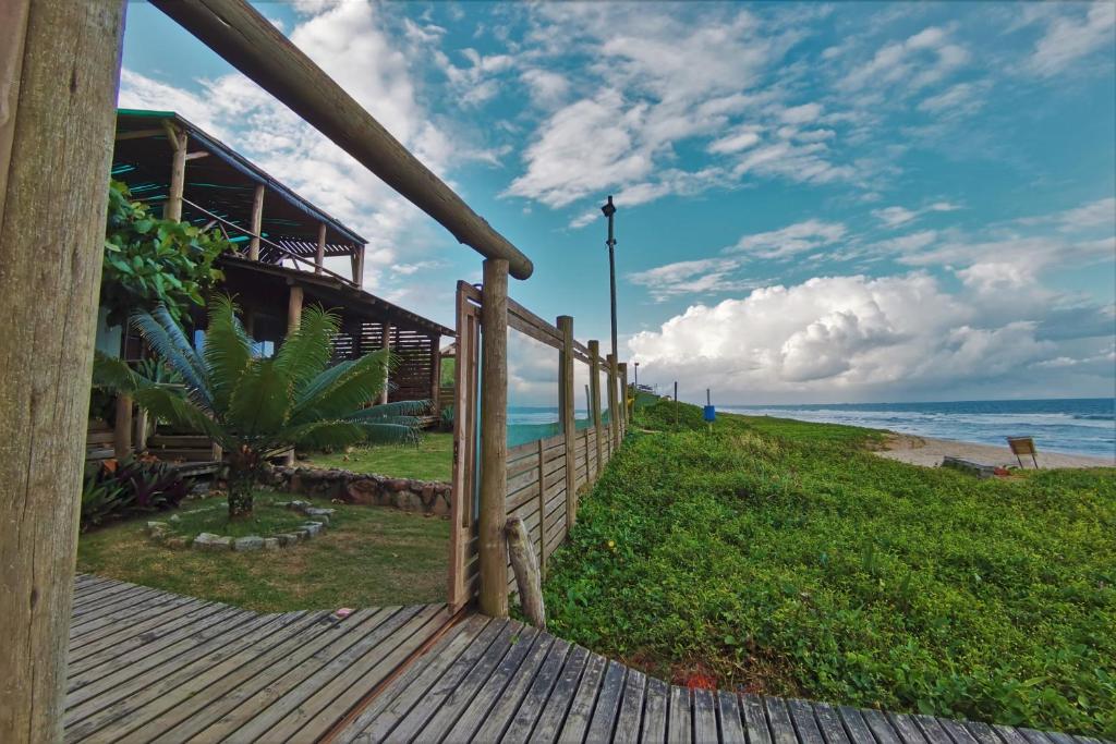 una pasarela de madera que conduce a una casa en la playa en Pousada La Luna - Frente Mar en Barra Velha