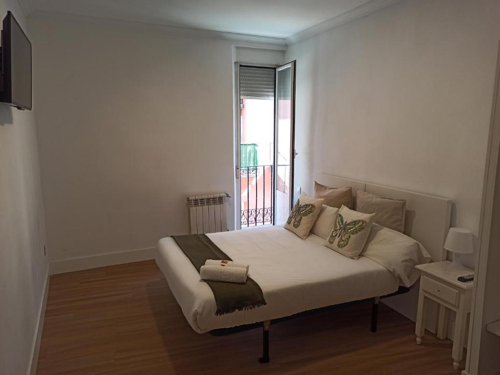 a white bedroom with a bed with a window at Pensión Estrella in Madrid