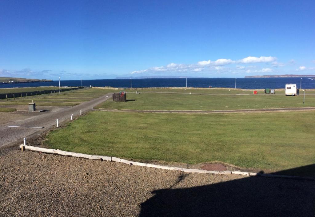 a large grassy field with the ocean in the background at Thurso Bay Holidays in Thurso