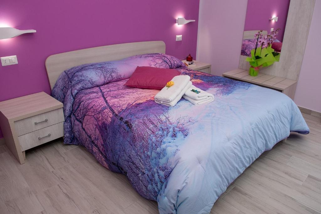una camera da letto viola con un letto con due asciugamani di Rainbow B&B a Campofelice di Roccella