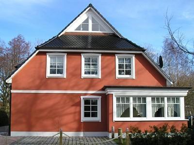 uma casa vermelha com um telhado preto e janelas brancas em Glebbe 66 _ Hus Suennschien em Zingst