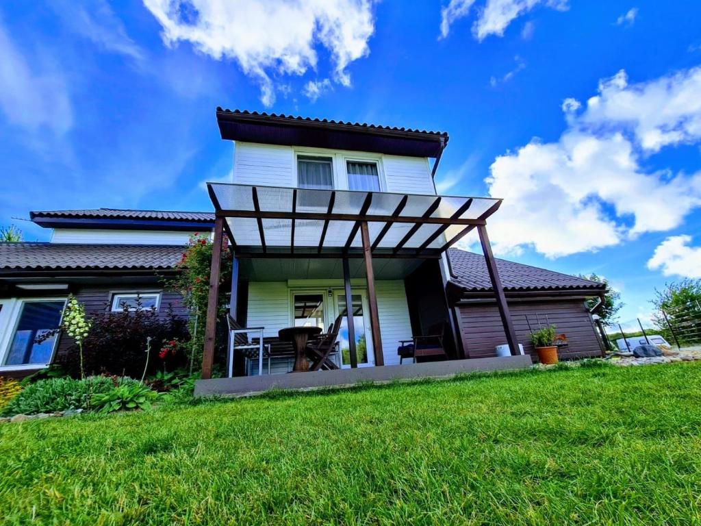 a house with a pergola on a lawn at Privati valda in Šventoji
