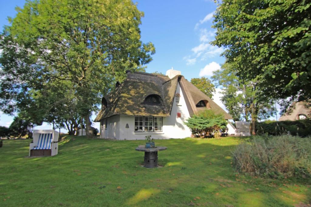 a house with a thatched roof on a lawn at Pesel im Friesenhaus Sieben-Linden ebenerdig in Archsum