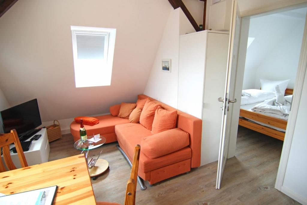 een woonkamer met een oranje bank en een slaapkamer bij Osten in Westerland