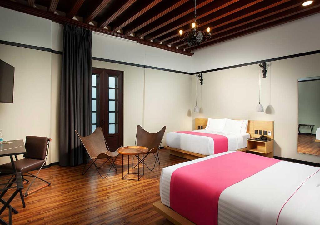 メキシコシティにあるHotel MX centroのベッド2台、テーブルと椅子が備わるホテルルームです。