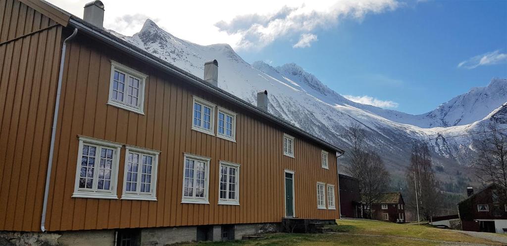 a brown house with mountains in the background at Lensmansgarden Marteinsgarden in Innfjorden