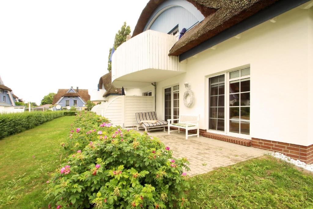 a white house with a chair on a patio at Wellnessresidenz Klaus Stoertebeke in Zingst