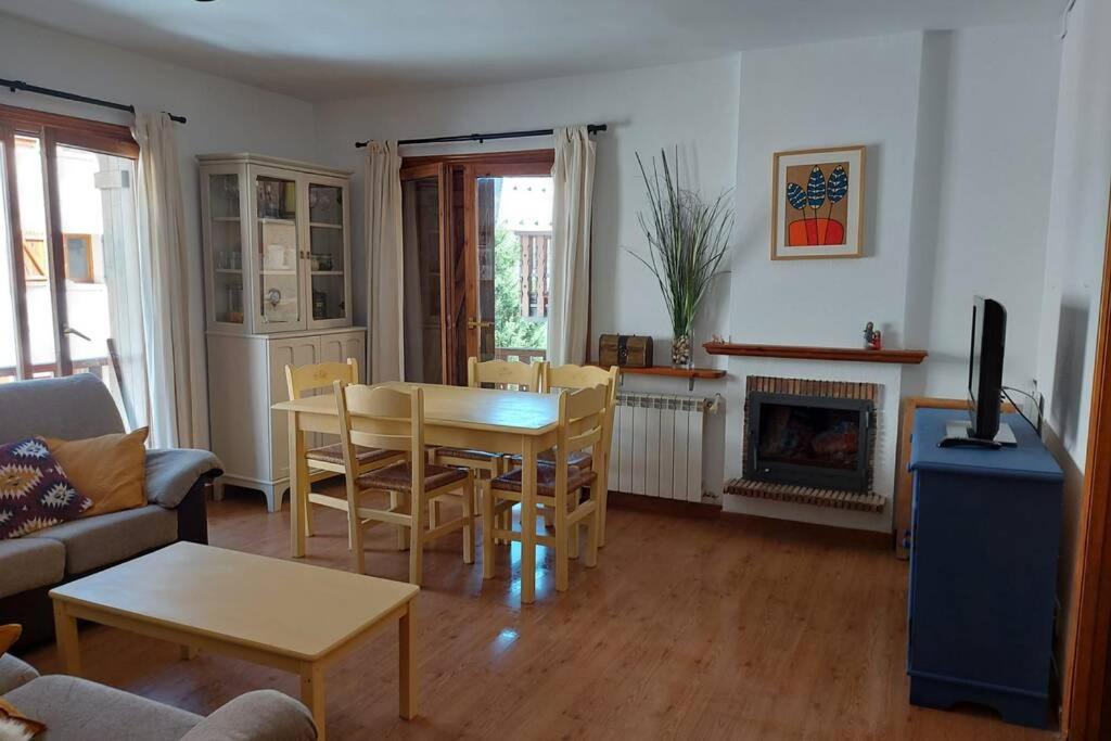 ein Wohnzimmer mit einem Tisch, Stühlen und einem Kamin in der Unterkunft Casa Bihotz - Bonito y céntrico apartamento con garaje en Sallent in Sallent de Gállego