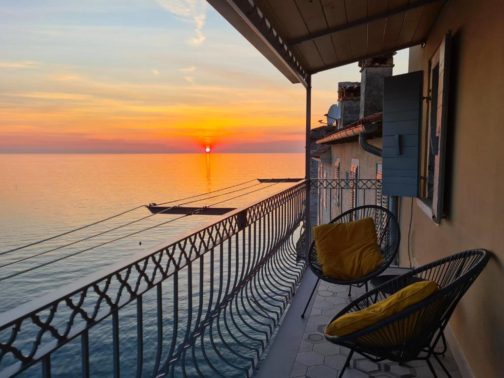 a balcony with two chairs and a sunset on the water at Apartment Panorama Antonia in Rovinj