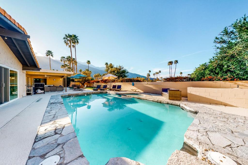 a swimming pool in a backyard with palm trees at Casa Via Estrella Permit# 4611 in Palm Springs