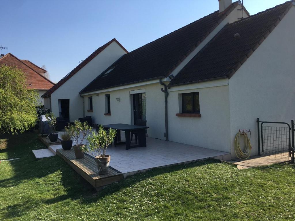 a house with a patio with a table in the yard at Gîte Le Chantecaille in Mer