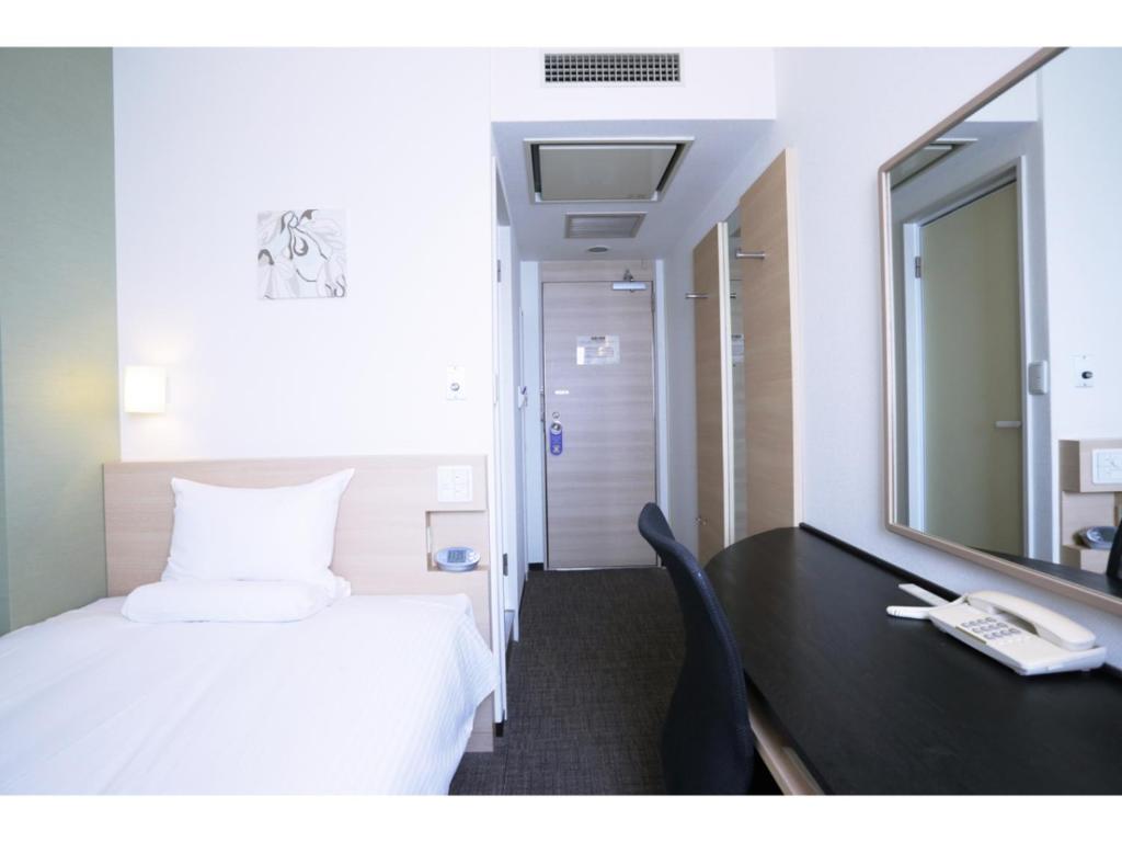 a bedroom with a bed and a desk with a mirror at Smile Hotel Tokyo Nihonbashi in Tokyo