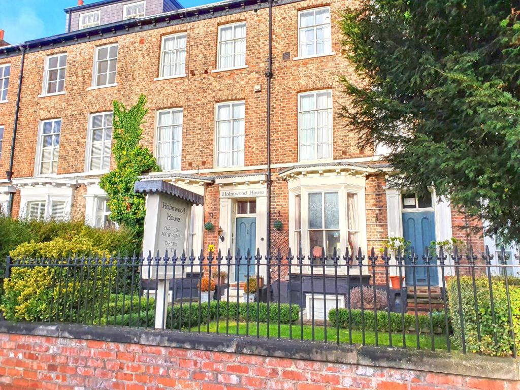 a brick house with blue doors and a fence at Holmwood House Guest Accommodation in York