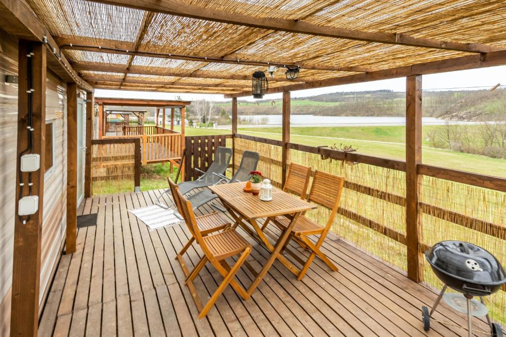 una terrazza in legno con tavolo e sedie. di Mobilheim Stella - Výrovická přehrada a Výrovice