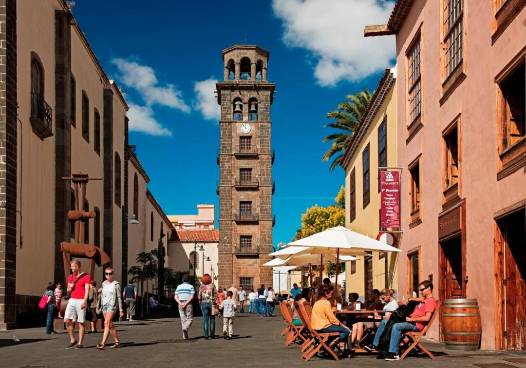 Holiday Home La Laguna Tenerife في لا لاغونا: برج الساعة مع زحمة الناس تمشي على الشارع