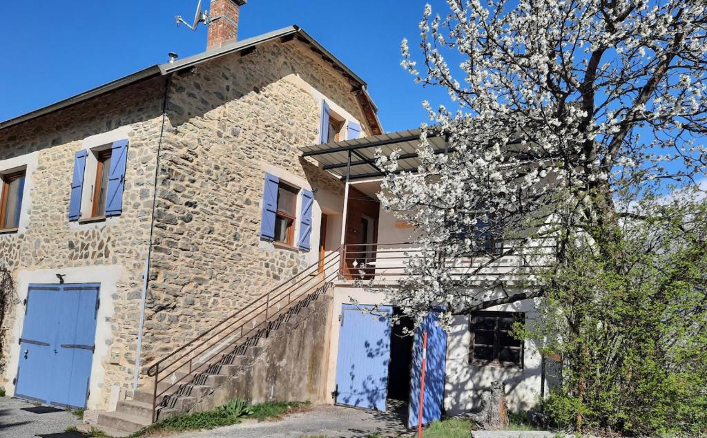 una casa in pietra con un albero fiorito davanti di Gite Noisette, Saint André d'Embrun a Embrun
