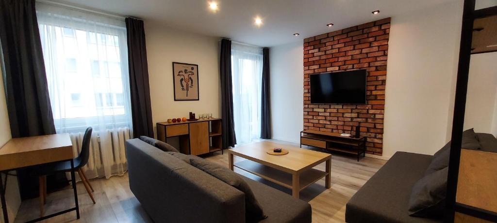 a living room with a couch and a brick wall at Apartament Grunwaldzka in Tuchola