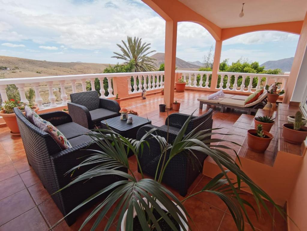 a porch with chairs and tables on a balcony at Casa LA GUALJAMA Tesejerague in Tesejerague