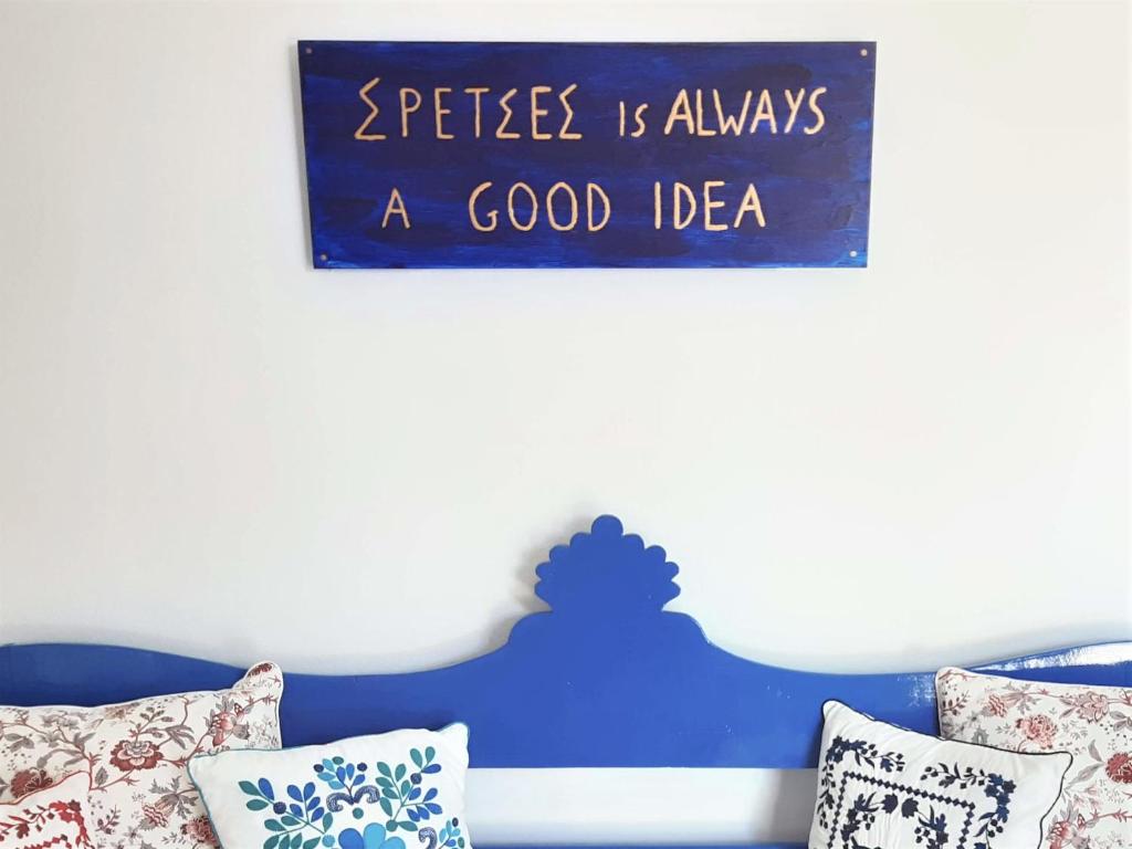 ein Schild an einer Wand über einem Bett mit Kissen in der Unterkunft Dapia Holiday Home in Spetses