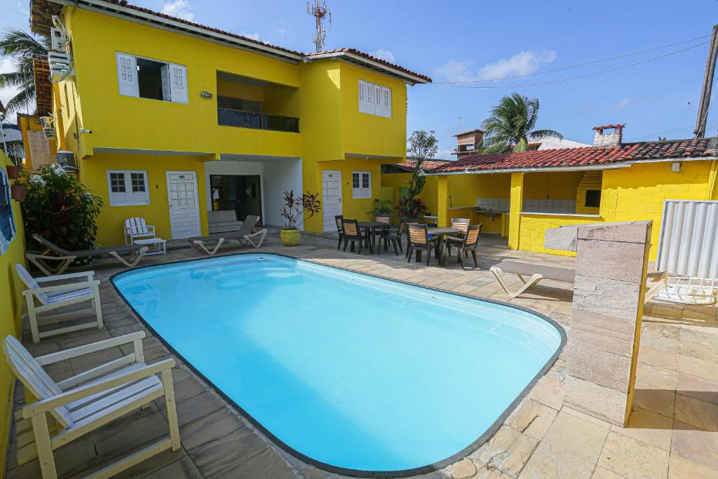 uma piscina em frente a uma casa com uma casa amarela em Pousada Sossego Suítes em Porto de Galinhas