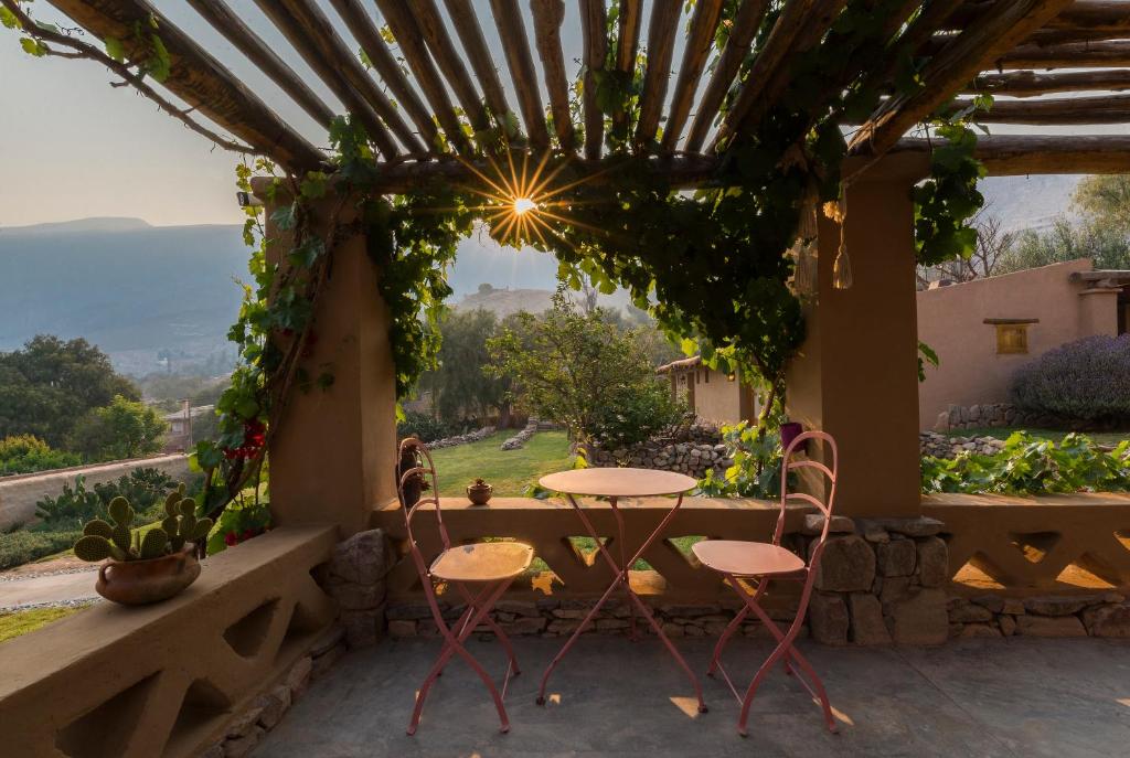 a table and chairs on a porch with a view at Posada de Luz in Tilcara