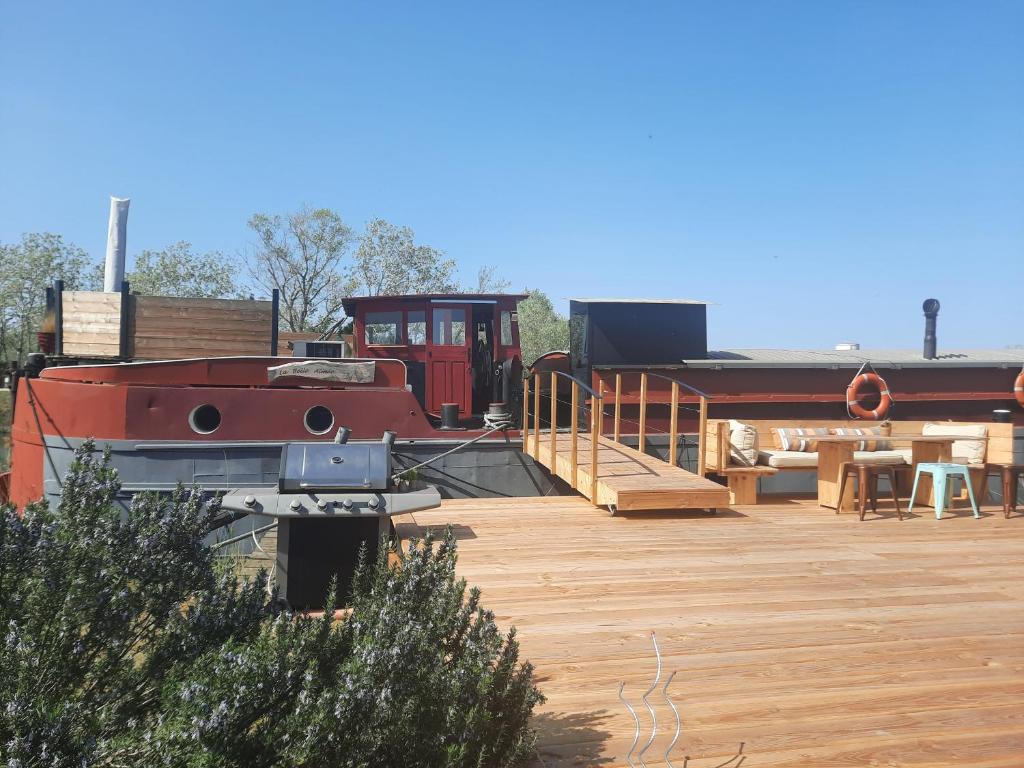 a boat sitting on a deck next to a house at Péniche La Belle Aimée in Aigues-Mortes