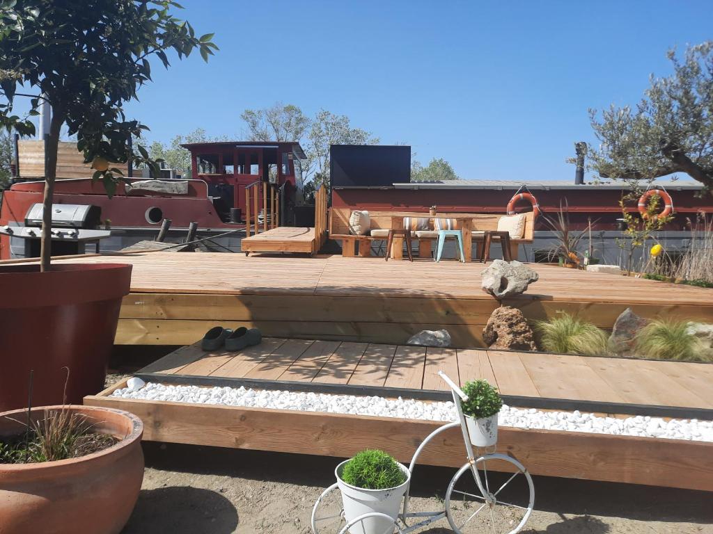 a patio with a wooden deck with a table and chairs at Péniche La Belle Aimée in Aigues-Mortes