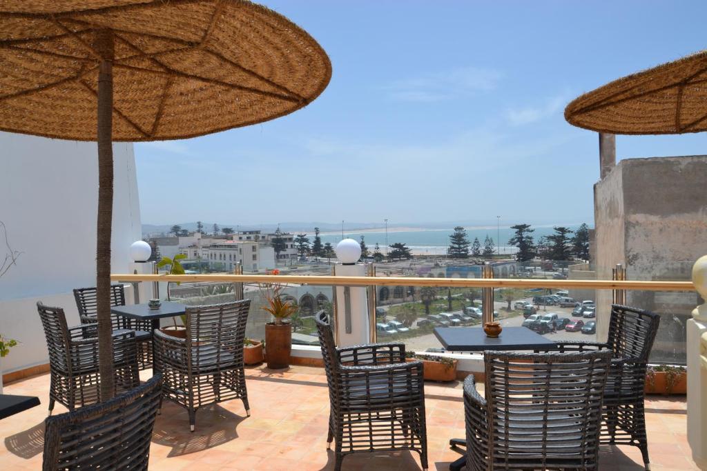 a patio with tables and chairs and umbrellas at Hotel Riad Ben Atar in Essaouira