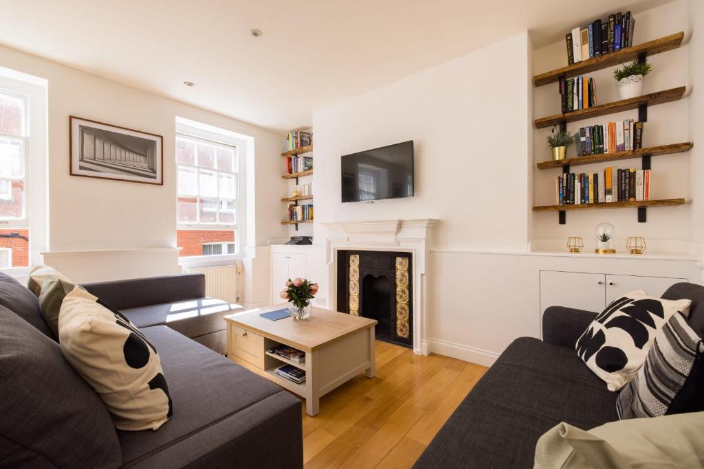 een woonkamer met een bank en een open haard bij Contemporary 1 Bedroom Bloomsbury Apartment in Londen