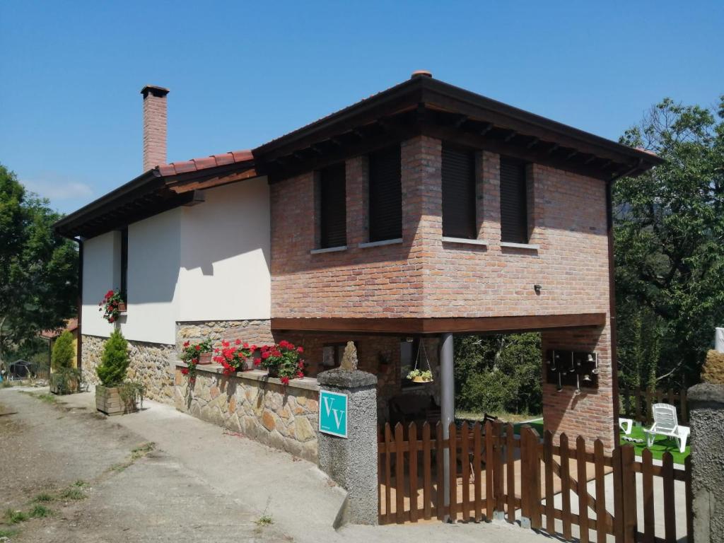 a small brick house with a wooden fence at la casina de Parres in San Juan de Parres