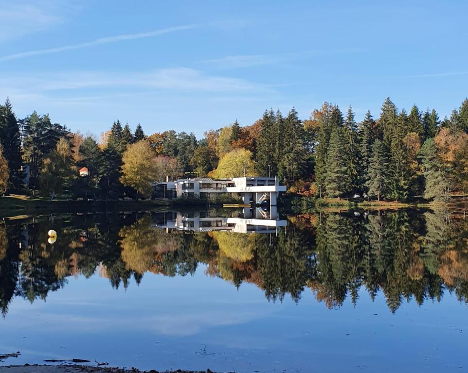 un reflejo de una casa en un lago en Hôtel Eden Lake, en Égletons