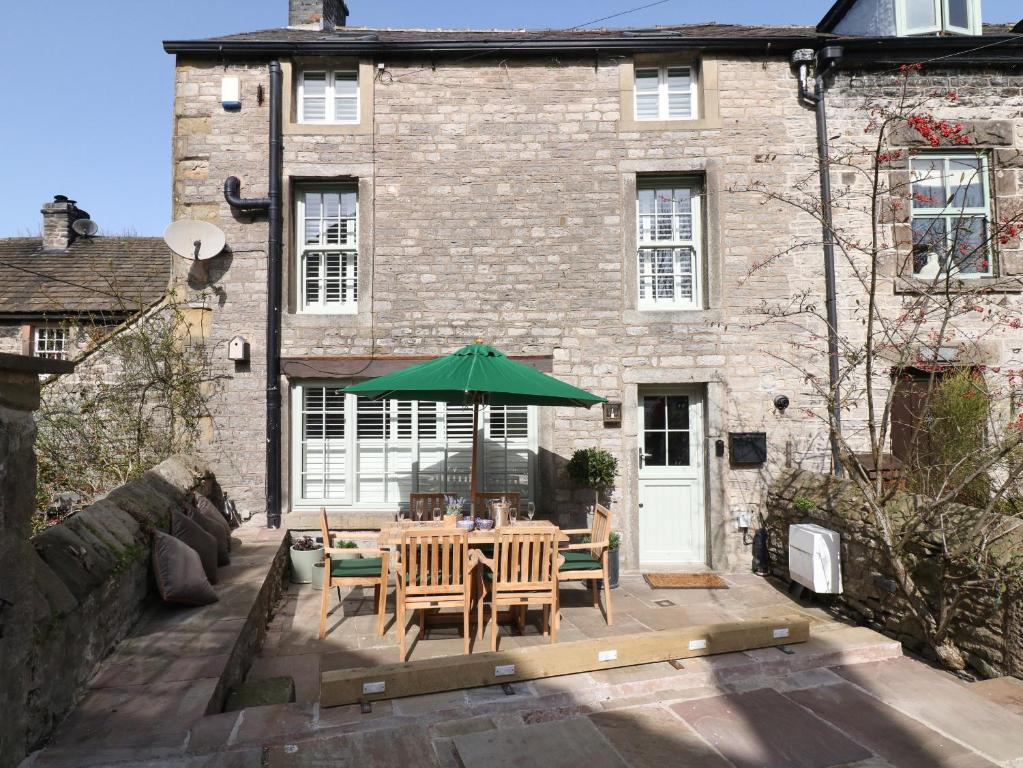 a table with a green umbrella in front of a building at Brookhouse in Castleton