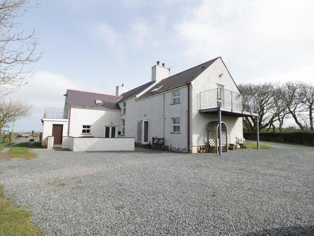 a large white house with a gravel driveway at Bodegri Cottage in Llanfflewyn