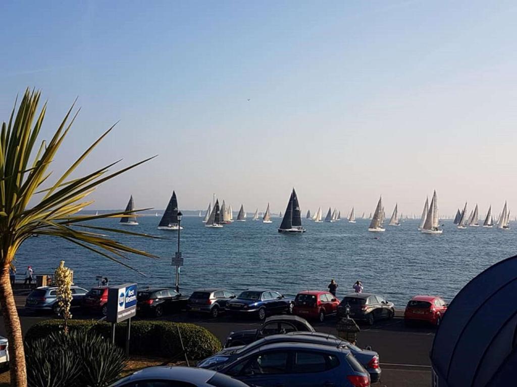 a group of sail boats in the water with cars at BEST WESTERN New Holmwood Hotel in Cowes