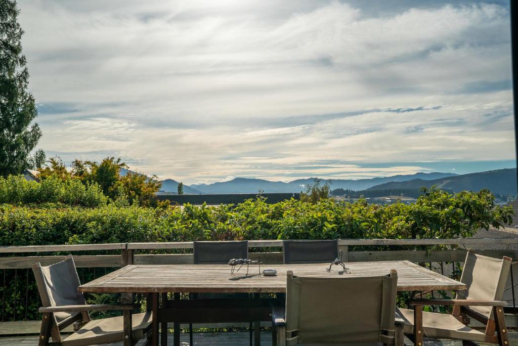 a wooden table and chairs with a view of the mountains at Goodall Crib - Wanaka Holiday Home in Wanaka