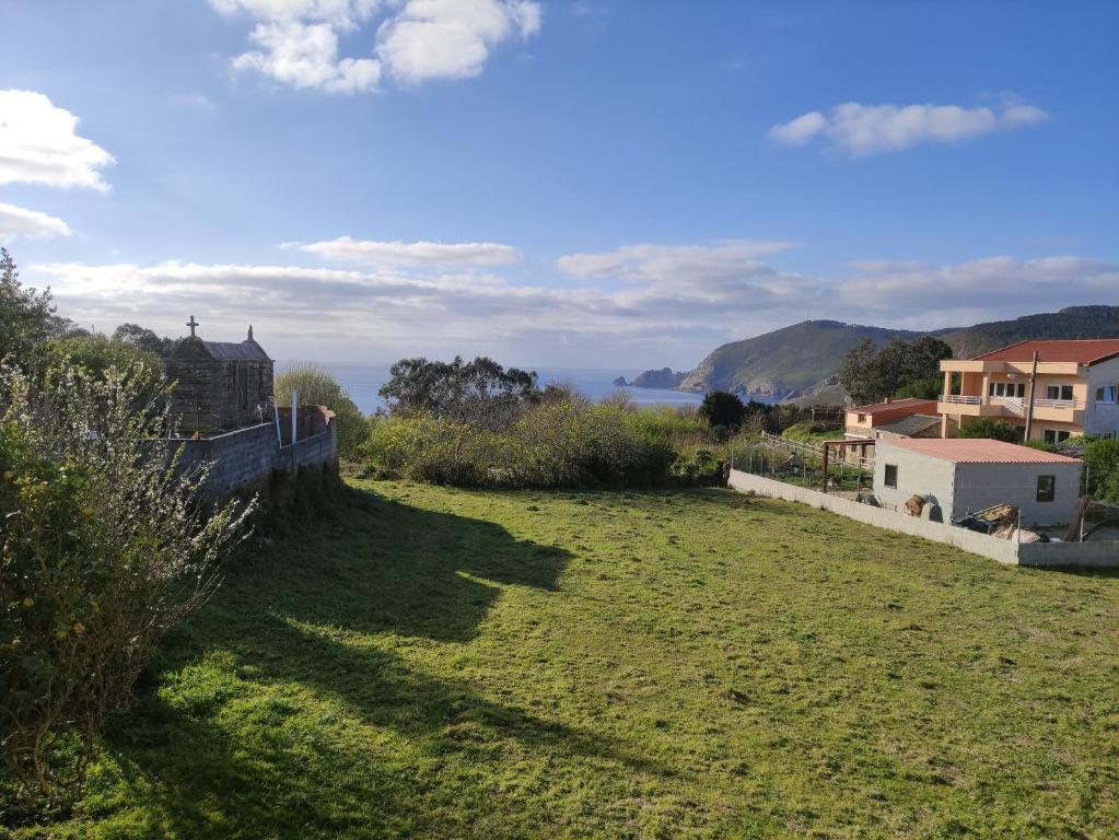a field of grass with a view of the ocean at Casa A Colorada cerca de la playa de Mar de Fora in Fisterra