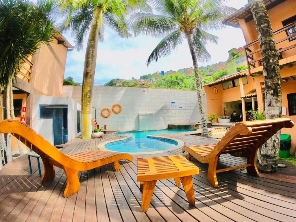taras z 2 krzesłami oraz basen z palmami w obiekcie Solar da Praia Pousada w mieście Arraial do Cabo