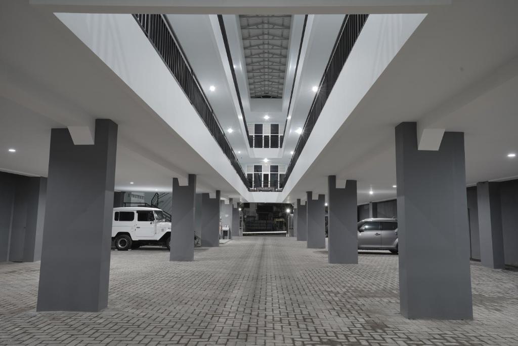 a hallway with pillars and cars in a parking lot at CASAKITA exclusive guest house in Yogyakarta