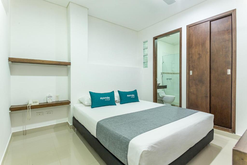1 dormitorio con 1 cama grande con almohadas azules en Hotel Ayenda Boutique Rio Mont, en Montería
